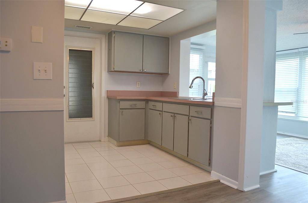 A kitchen features gray cabinets, pink countertops, white tile flooring, and a drop ceiling — 9632 42ND STREET N, PINELLAS PARK, FL