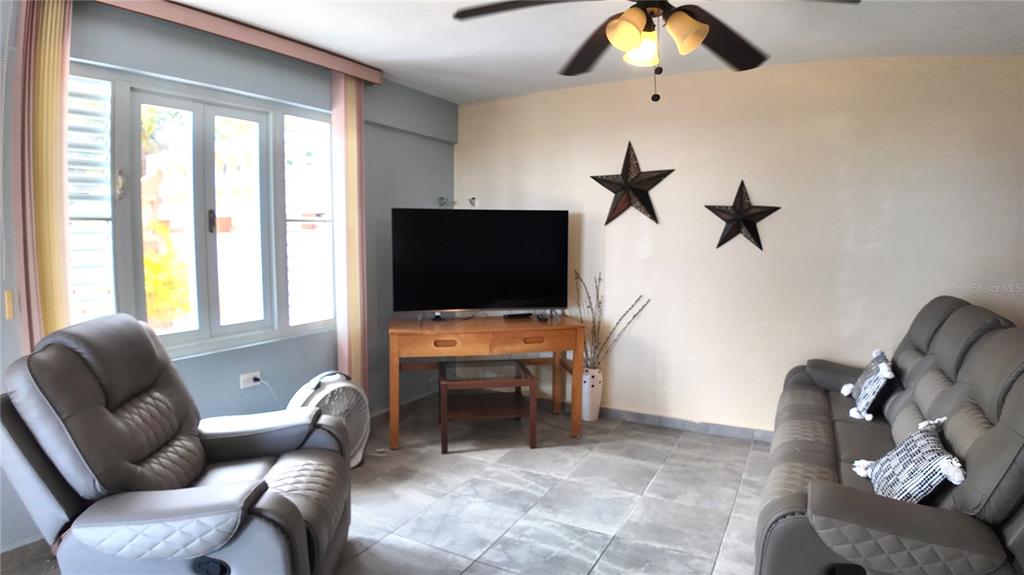 A living room features gray tile floors, a recliner, a sofa, and a television stand — Buzon 6312 Bo. Jaguay CARR. 412 KM 6.0, RINCON, PR