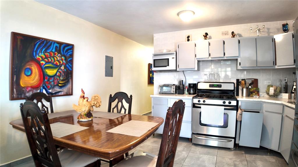 A dining area with a wooden table sits adjacent to a kitchen with gray cabinets — Buzon 6312 Bo. Jaguay CARR. 412 KM 6.0, RINCON, PR