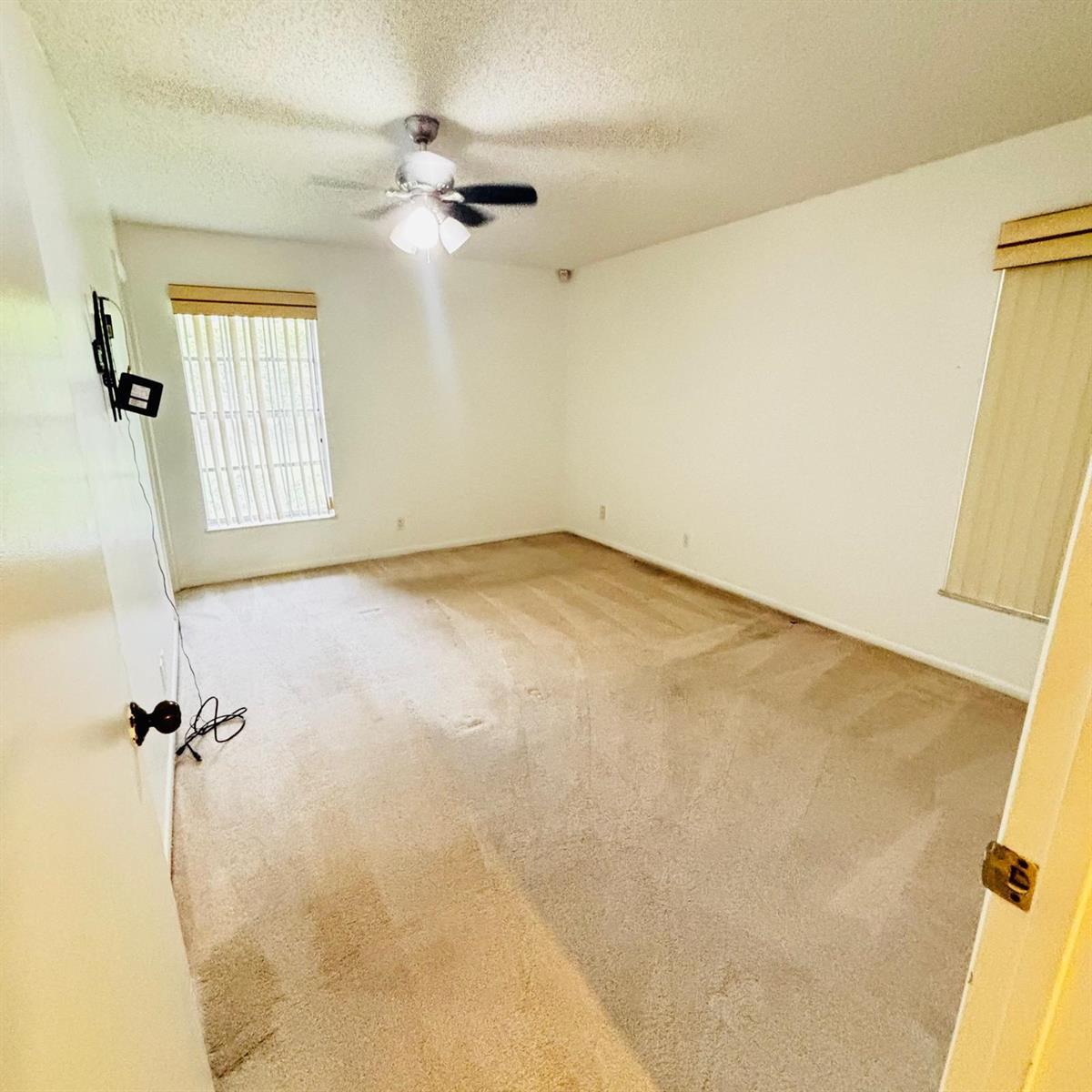 An empty bedroom features beige carpeting, white walls, a ceiling fan, and two windows — 386 Bennington Lane, Lake Worth FL 33467, LAKE WORTH, FL