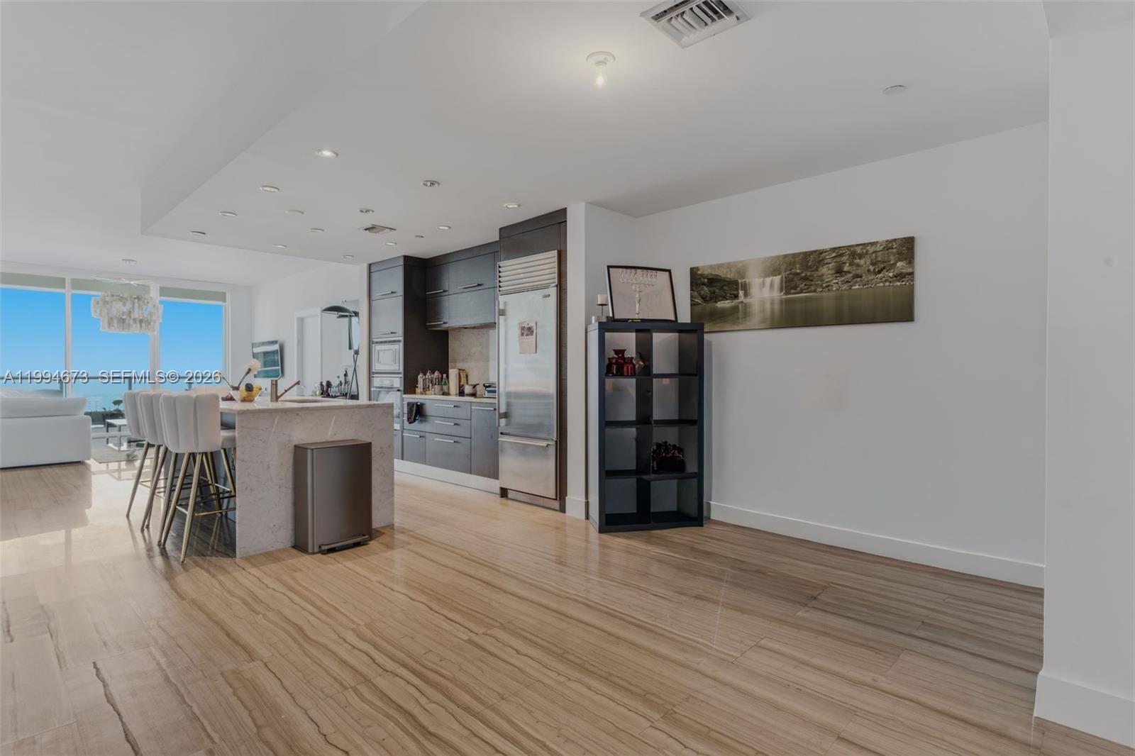 A modern kitchen features a marble island, dark cabinetry, and light wood-look flooring — 900 Biscayne Blvd # 4308, Miami FL 33132, MIAMI, FL