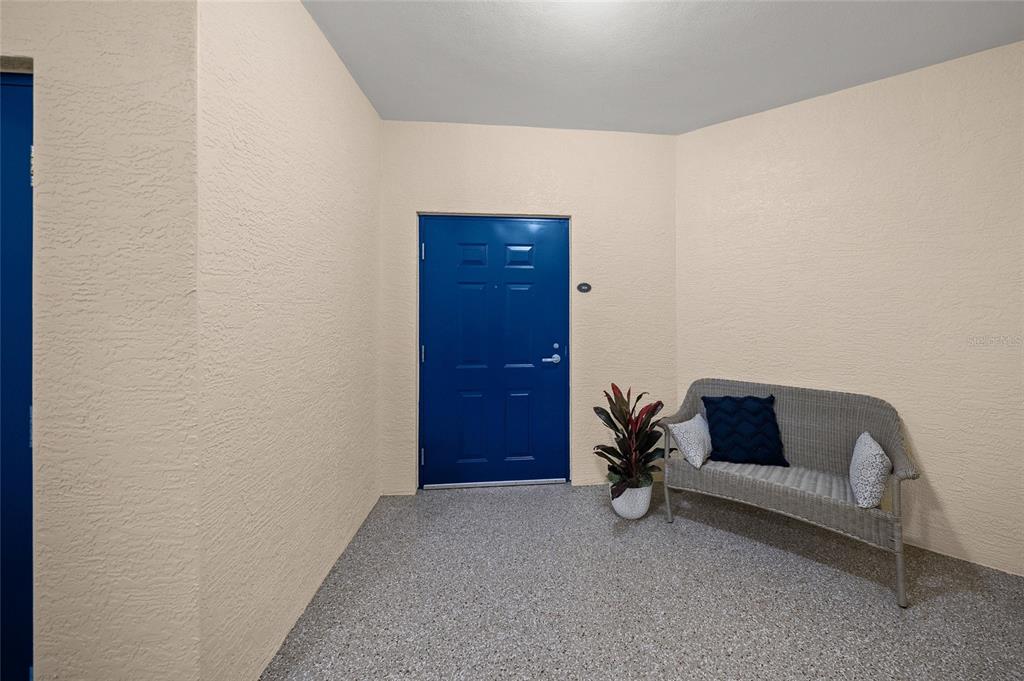 A small entryway features a blue door, a wicker bench, and speckled flooring — 14021 BELLAGIO WAY UNIT 309, OSPREY, FL