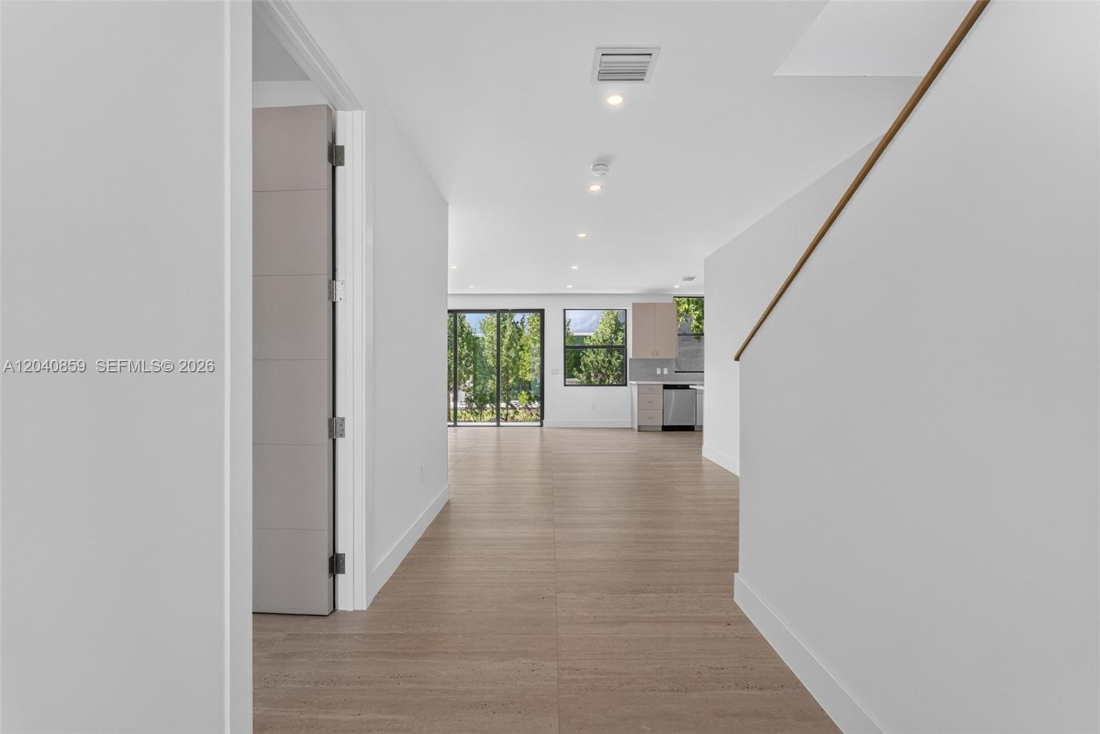 A hallway with light wood-look flooring leads toward an open kitchen and living area — 2240 SW 13th St, Miami FL 33145, MIAMI, FL