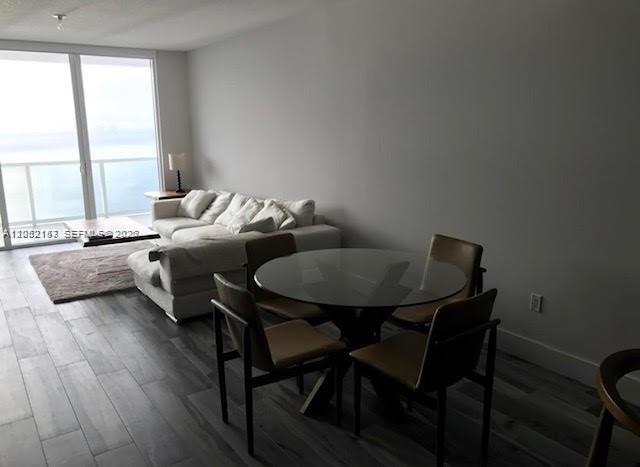 A living and dining area features wood-look tile floors, a white sofa, and ocean views — 600 NE 27th St # 2202, Miami FL 33137, MIAMI, FL