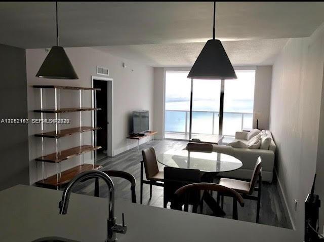 A kitchen view overlooks a dining area, living room, and balcony with a water view — 600 NE 27th St # 2202, Miami FL 33137, MIAMI, FL