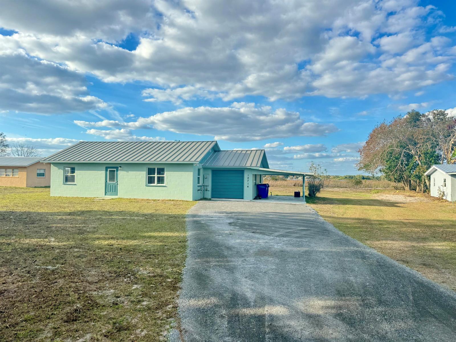 A light green single-story house with a metal roof, attached garage, and a paved driveway — 12714 U.s. 98, Sebring FL 33876, SEBRING, FL