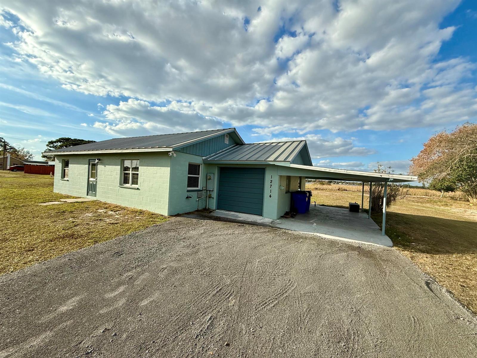 A light green concrete block house features a metal roof, garage, and attached carport — 12714 U.s. 98, Sebring FL 33876, SEBRING, FL