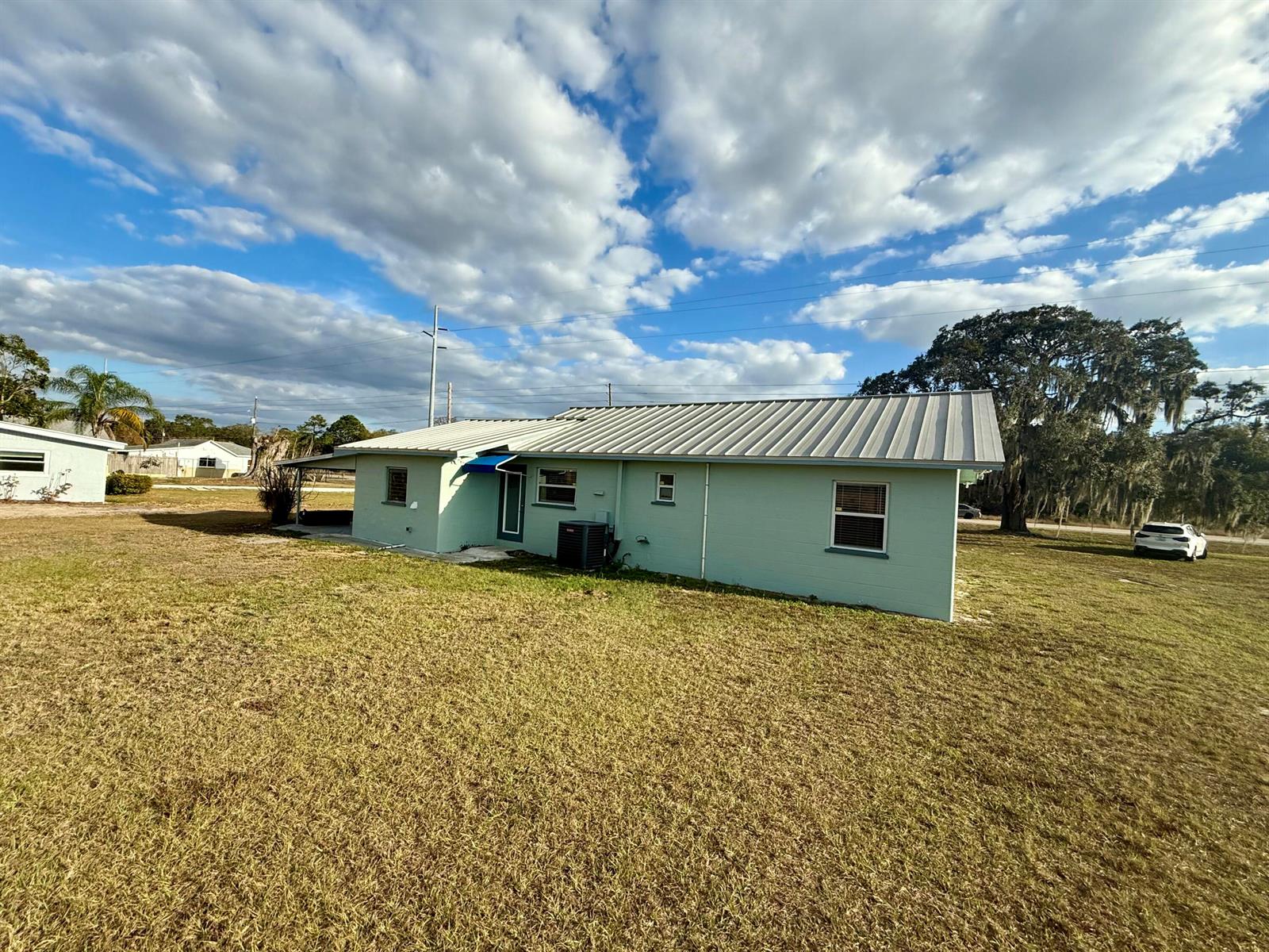 A light green, single-story house with a metal roof sits on a large grassy lot — 12714 U.s. 98, Sebring FL 33876, SEBRING, FL