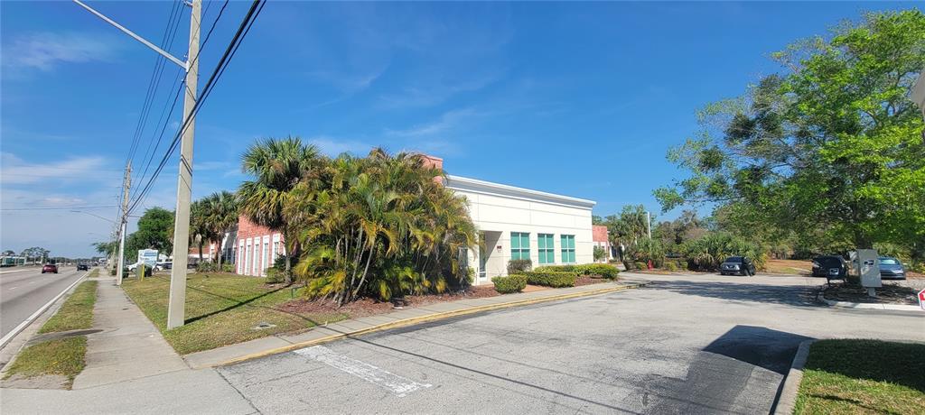 A low-rise commercial building with a white facade sits behind palm trees near a road — 1277 SEMORAN BLVD UNIT 118, ORLANDO, FL
