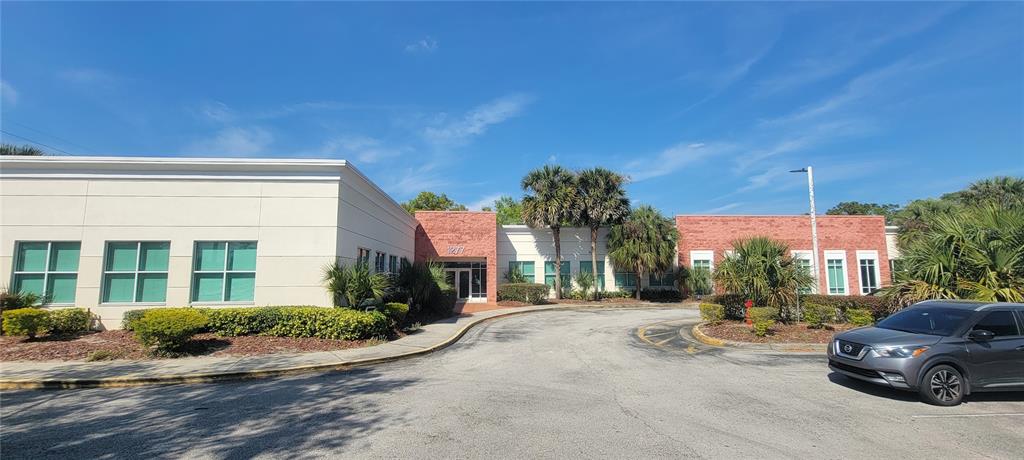 A single-story commercial building features a mix of beige stucco and red brick exterior walls — 1277 SEMORAN BLVD UNIT 118, ORLANDO, FL