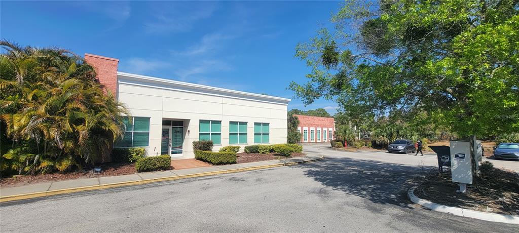 A one-story commercial building with white walls and green-tinted windows sits beside a parking lot — 1277 SEMORAN BLVD UNIT 118, ORLANDO, FL
