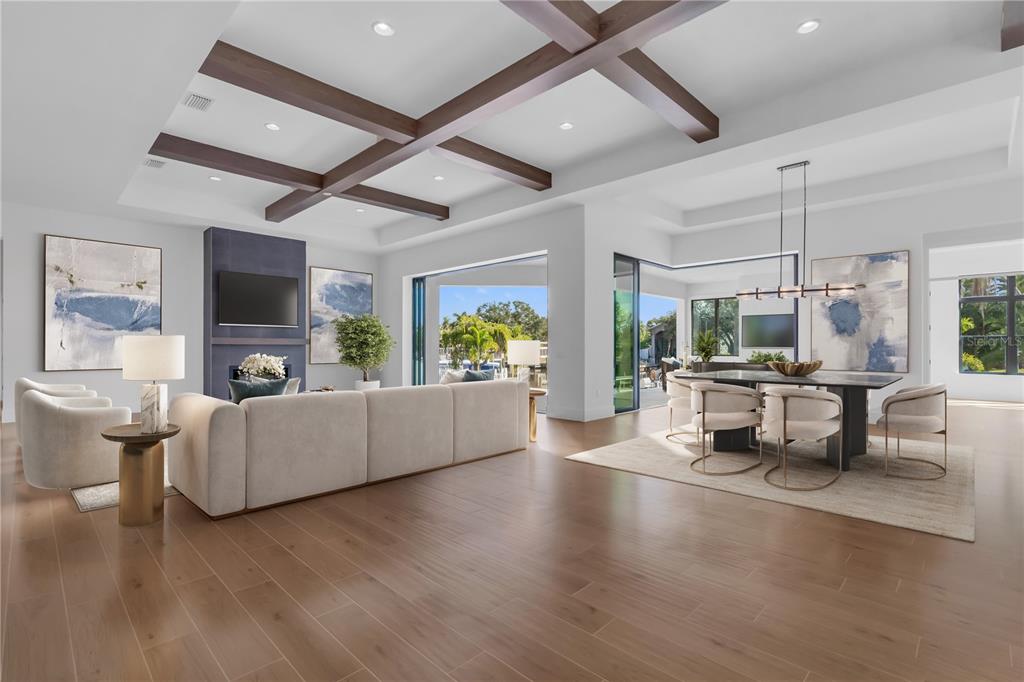 An open-concept living and dining area features wood-beam ceilings, hardwood floors, and large sliding doors — 7125 WESTMORELAND DRIVE, SARASOTA, FL