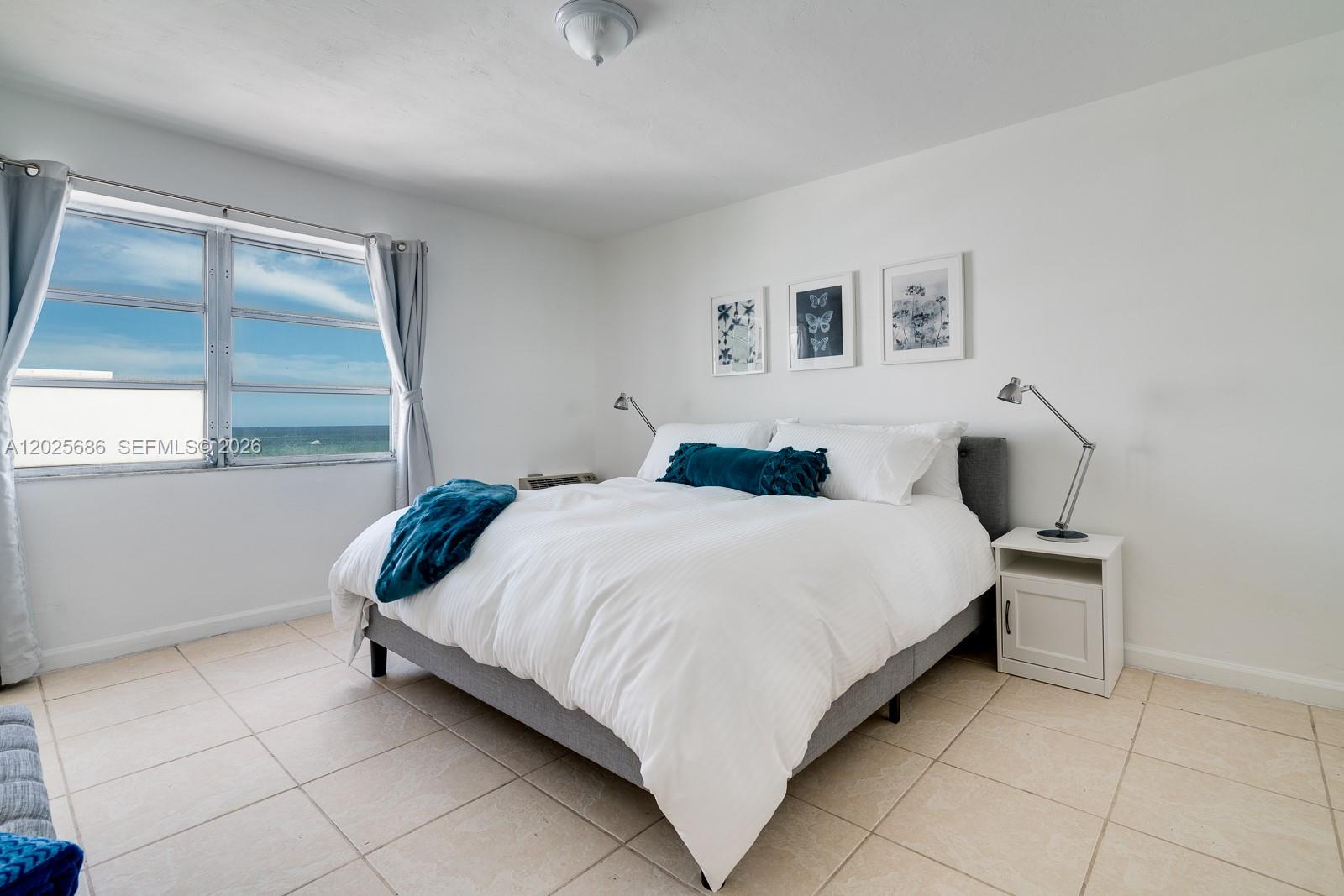 A bedroom features a bed with white bedding, a blue throw, and an ocean view — 3100 Collins Ave # 1101, Miami Beach FL 33140, MIAMI BEACH, FL
