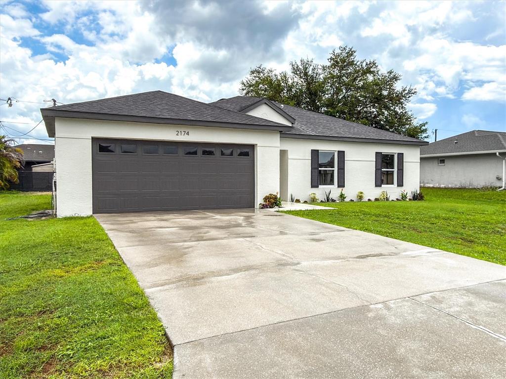 A single-story house with a white stucco exterior, dark gray garage door, and dark shutters — 2174 BRUBECK ROAD, NORTH PORT, FL