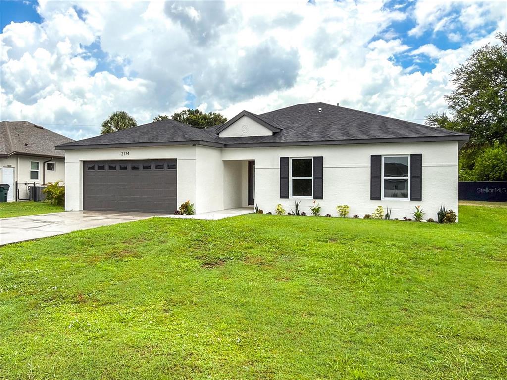 A single-story house with a white stucco exterior, dark roof, and a two-car garage — 2174 BRUBECK ROAD, NORTH PORT, FL