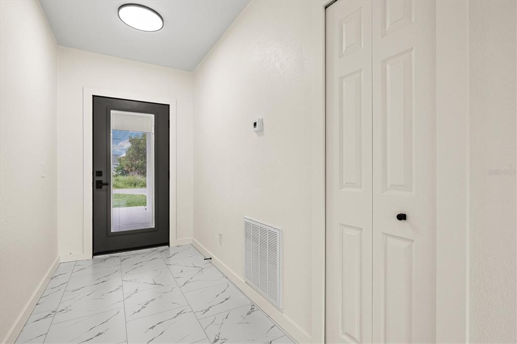 An entryway features white marble-look tile flooring, a black front door, and a white closet — 2174 BRUBECK ROAD, NORTH PORT, FL