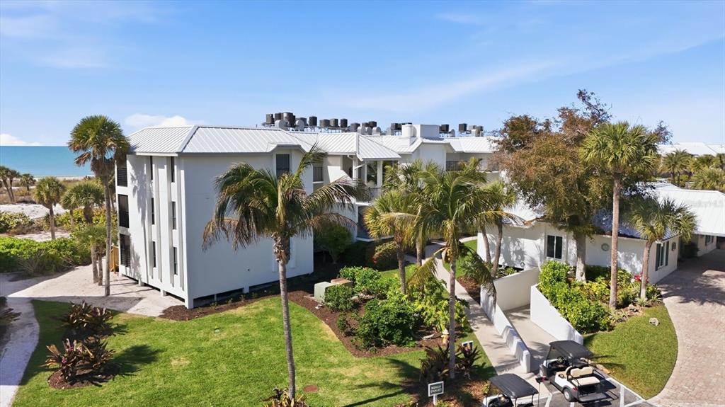 An aerial view shows a multi-story white building with palm trees and a golf cart — 5000 GASPARILLA ROAD UNIT BC205, BOCA GRANDE, FL