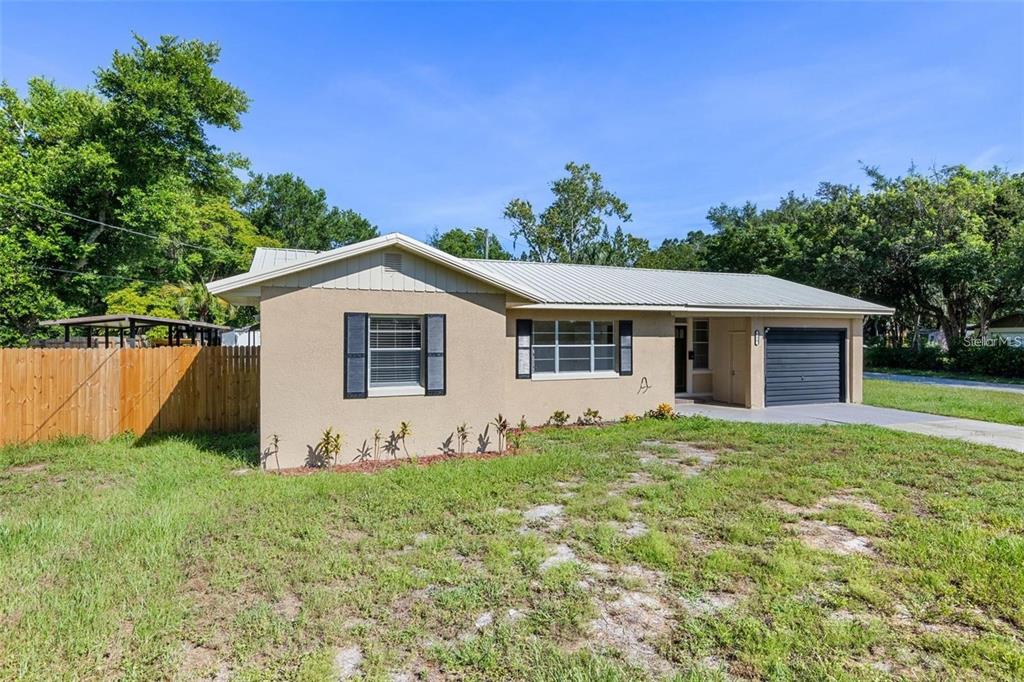 A single-story house with a tan stucco exterior, a metal roof, and a one-car garage — 236 ELDORADO DRIVE, DEBARY, FL