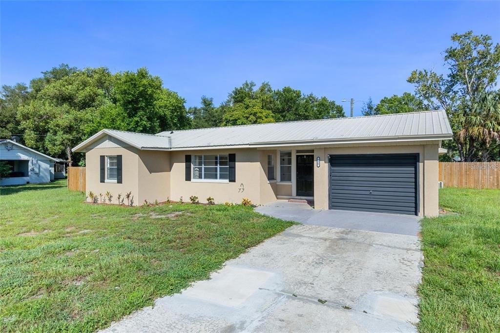 A single-story house with a tan exterior, metal roof, and an attached one-car garage — 236 ELDORADO DRIVE, DEBARY, FL