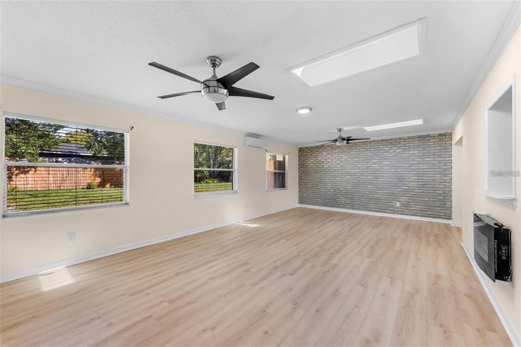 A spacious living room features light wood-look flooring, a brick accent wall, and two ceiling fans — 236 ELDORADO DRIVE, DEBARY, FL