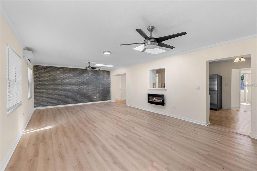 A living room features light wood flooring, a dark brick accent wall, and a wall-mounted fireplace — 236 ELDORADO DRIVE, DEBARY, FL