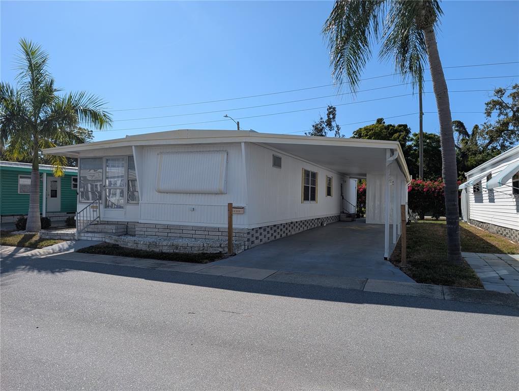 A white mobile home with a carport and a small brick-walled front patio — 82010 A STREET N UNIT 10, PINELLAS PARK, FL