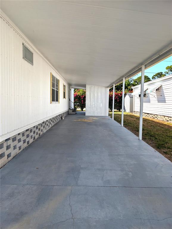 A long, covered concrete carport runs alongside the white exterior wall of a mobile home — 82010 A STREET N UNIT 10, PINELLAS PARK, FL