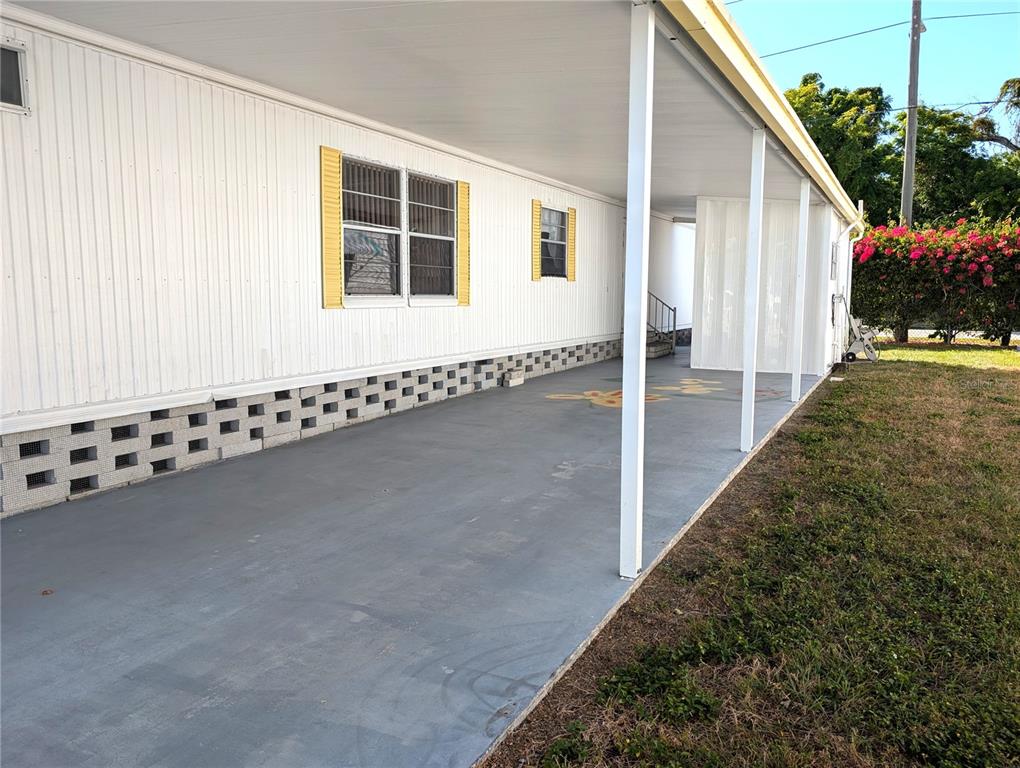 A white mobile home features a covered concrete carport with decorative block skirting — 82010 A STREET N UNIT 10, PINELLAS PARK, FL