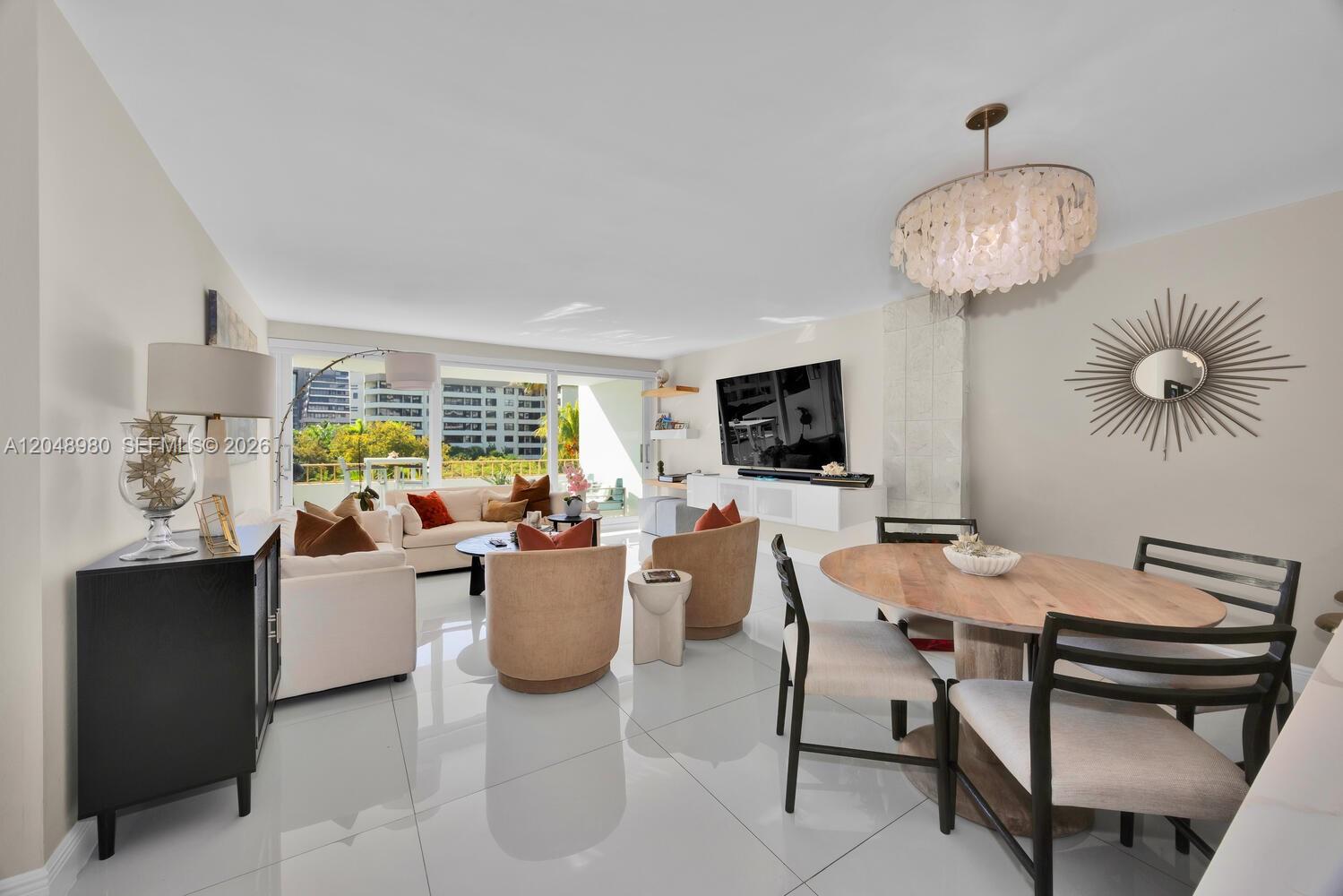 A bright living and dining area features white tile floors, modern furniture, and balcony views — 155 Ocean Lane Dr # 413, Key Biscayne FL 33149, KEY BISCAYNE, FL