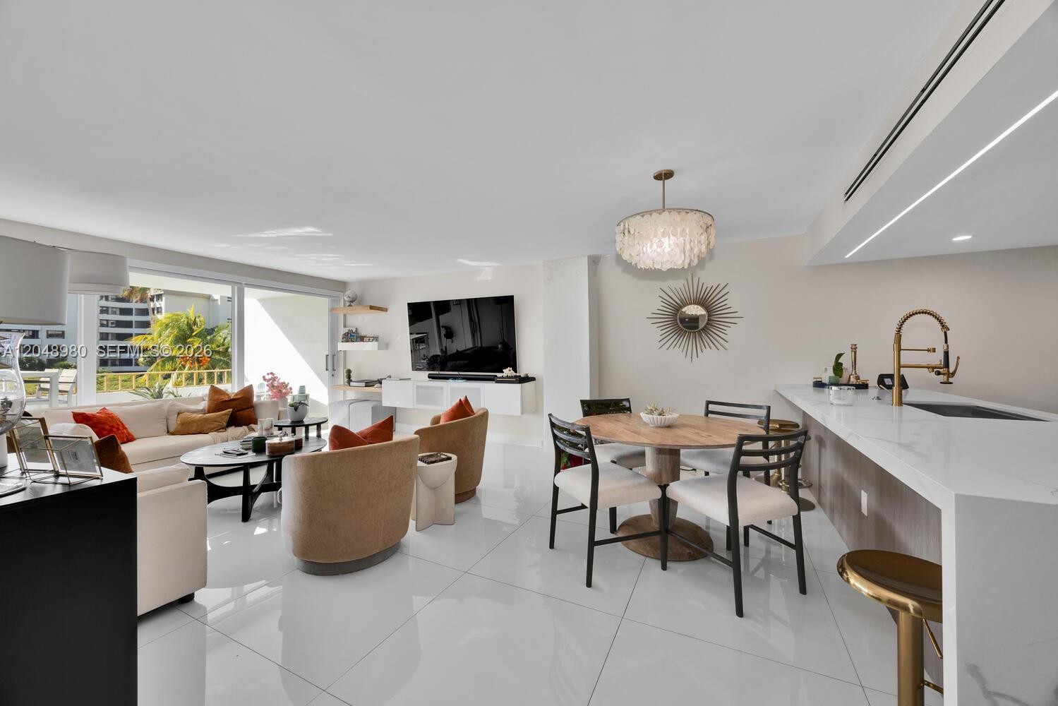 An open-concept living and dining area features white tile floors, modern furniture, and a kitchen — 155 Ocean Lane Dr # 413, Key Biscayne FL 33149, KEY BISCAYNE, FL