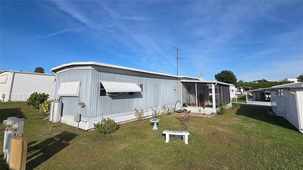 A light blue mobile home with a screened-in porch sits on a grassy lot — 7139 EL CONQUISTADOR STREET, ZEPHYRHILLS, FL