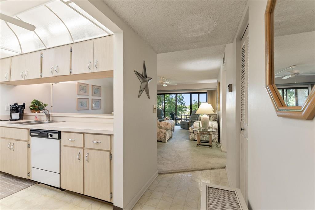 A kitchen with light wood cabinets opens into a carpeted living area with a balcony — 206 LA CASA UNIT 206, LAKE WALES, FL