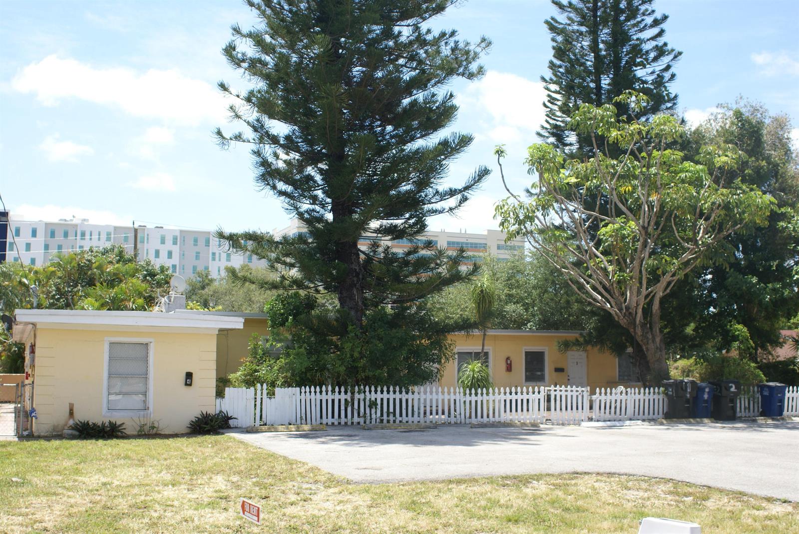 A yellow single-story building with a white picket fence and a large pine tree — 224 SE 9th Court # 4, Hallandale Beach FL 33009, HALLANDALE BEACH, FL