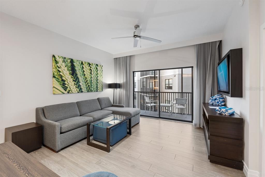 A living room features a gray sectional sofa, glass coffee table, and a balcony view — 14501 GROVE RESORT AVENUE UNIT 2607, WINTER GARDEN, FL