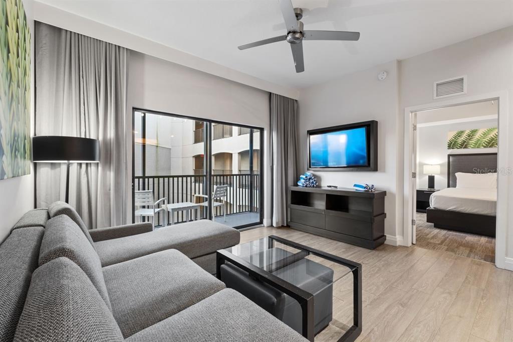 A living room with a gray sectional sofa, glass coffee table, and balcony access — 14501 GROVE RESORT AVENUE UNIT 2607, WINTER GARDEN, FL