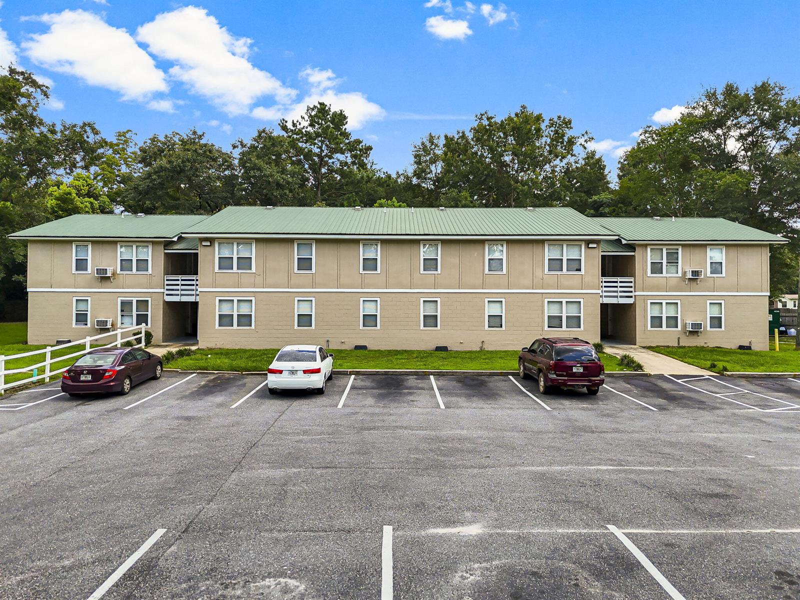 A two-story apartment building with a green metal roof sits behind a paved parking lot — 872 Deer Wood Lane, FL 32428, FL