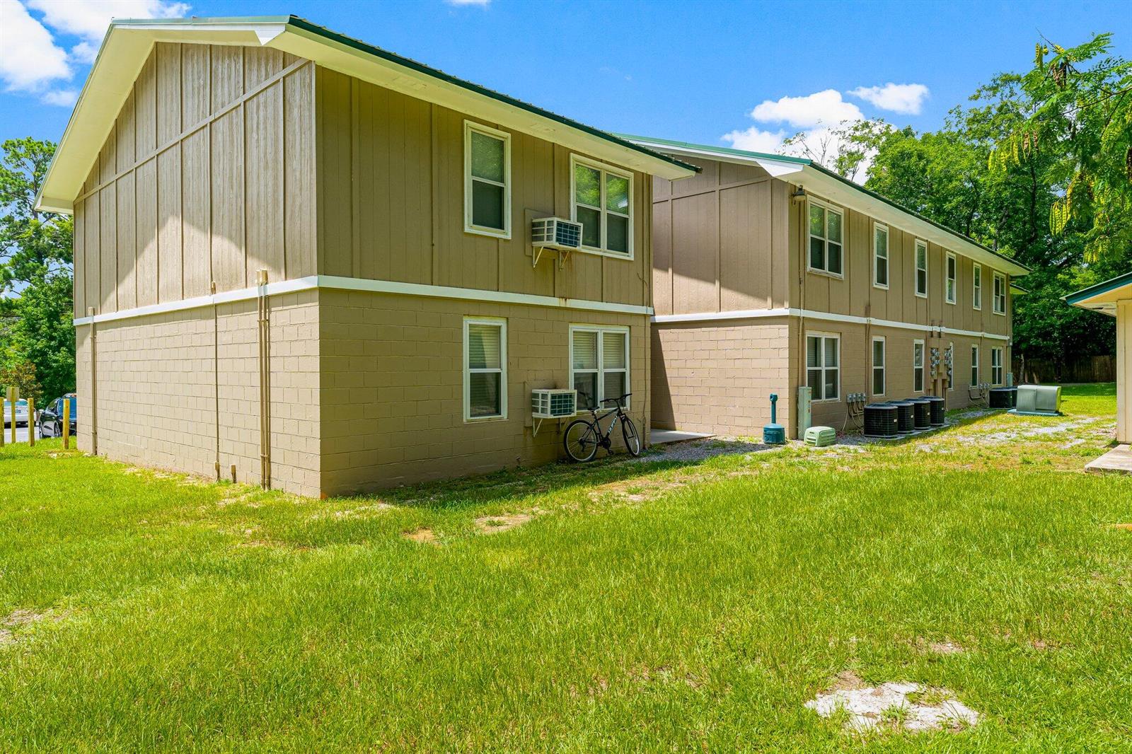A two-story apartment building with tan siding and concrete block walls sits on a lawn — 872 Deer Wood Lane, FL 32428, FL