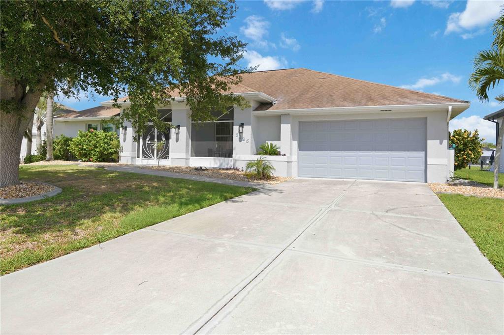 A single-story house with a light-colored exterior, a two-car garage, and a concrete driveway — 5186 FORBES TERRACE, PORT CHARLOTTE, FL