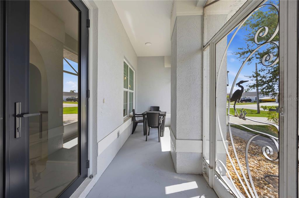 A covered porch features a gray floor, a decorative screen door, and a small dining set — 5186 FORBES TERRACE, PORT CHARLOTTE, FL