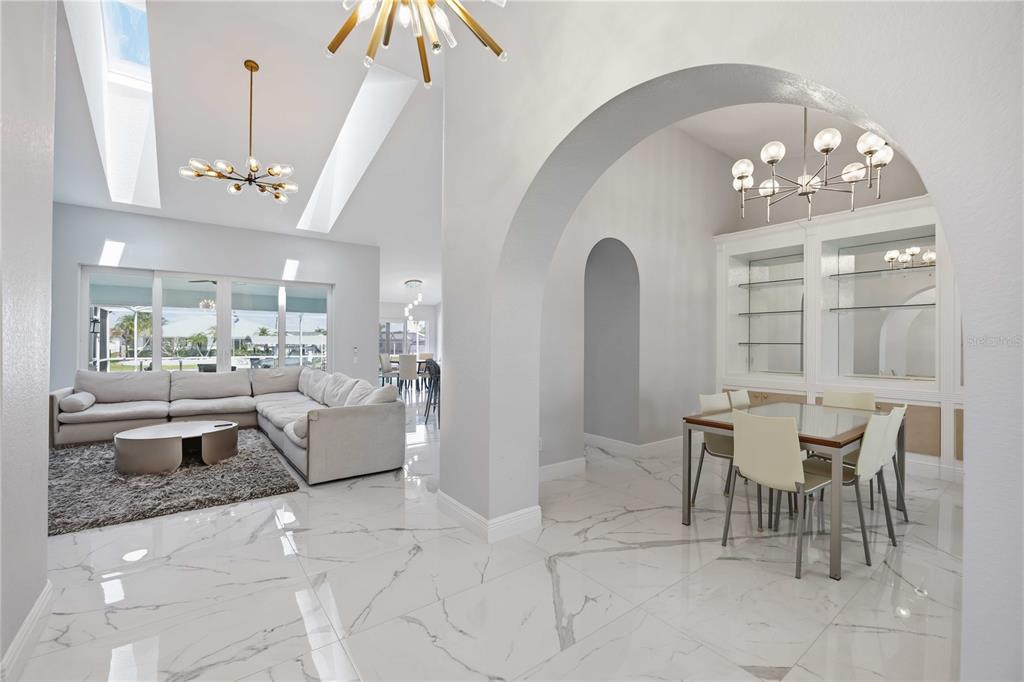 A bright, open-concept living and dining area features white marble flooring and arched architectural details — 5186 FORBES TERRACE, PORT CHARLOTTE, FL