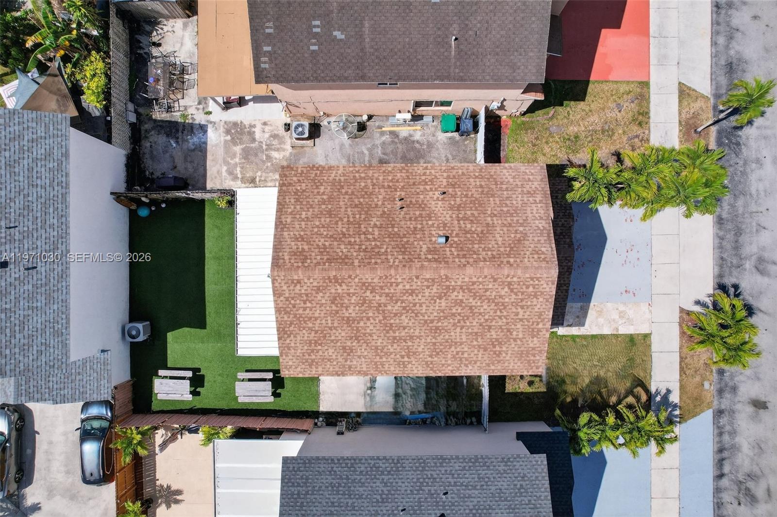 An aerial view shows a house with a brown shingled roof, artificial turf, and palm trees — 13758 SW 160th Ter, Miami FL 33177, MIAMI, FL