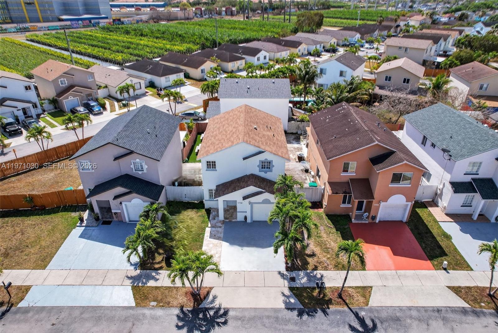 An aerial view shows three two-story suburban houses with driveways and palm trees in front — 13758 SW 160th Ter, Miami FL 33177, MIAMI, FL