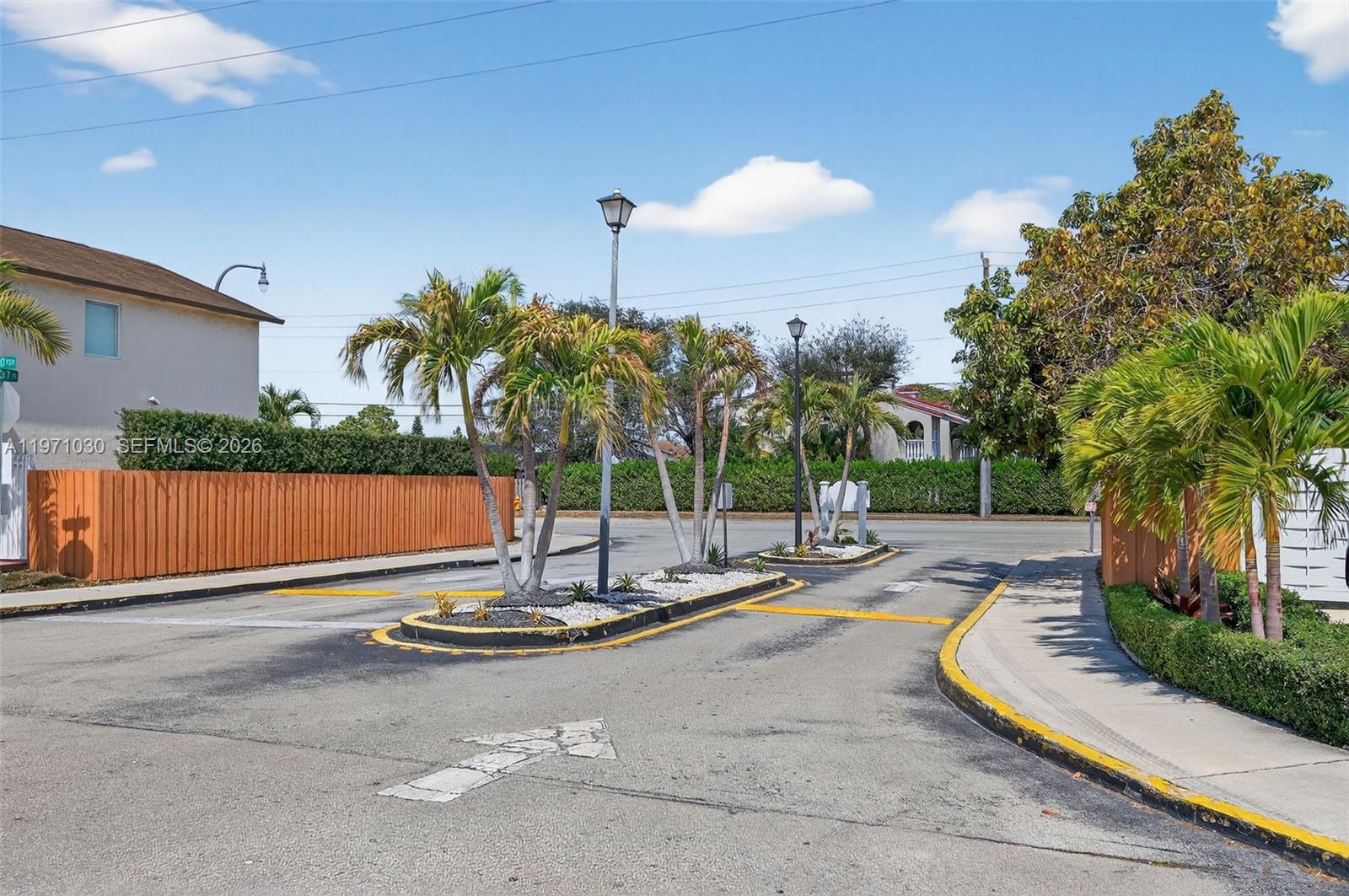A paved entrance features a landscaped median with palm trees and street lamps — 13758 SW 160th Ter, Miami FL 33177, MIAMI, FL
