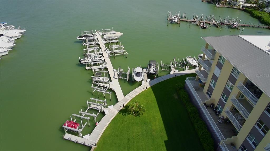 An aerial view shows a multi-story building with a private boat dock and marina — 423 150TH AVENUE UNIT 1405, MADEIRA BEACH, FL