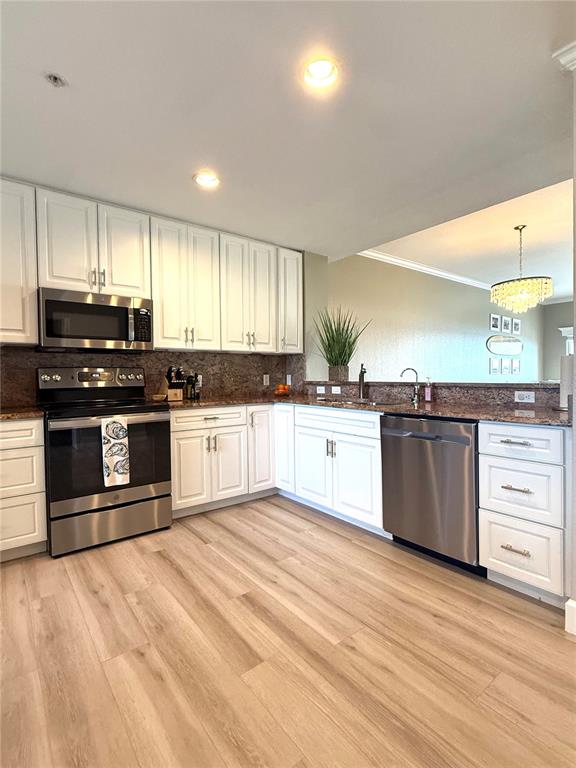 A kitchen features white cabinets, stainless steel appliances, and light wood-look flooring — 423 150TH AVENUE UNIT 1405, MADEIRA BEACH, FL