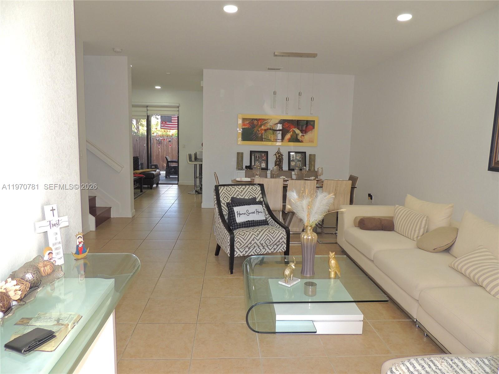 A living room and dining area feature tile floors, a glass coffee table, and neutral furniture — 11301 NW 88th Ter, Doral FL 33178, DORAL, FL