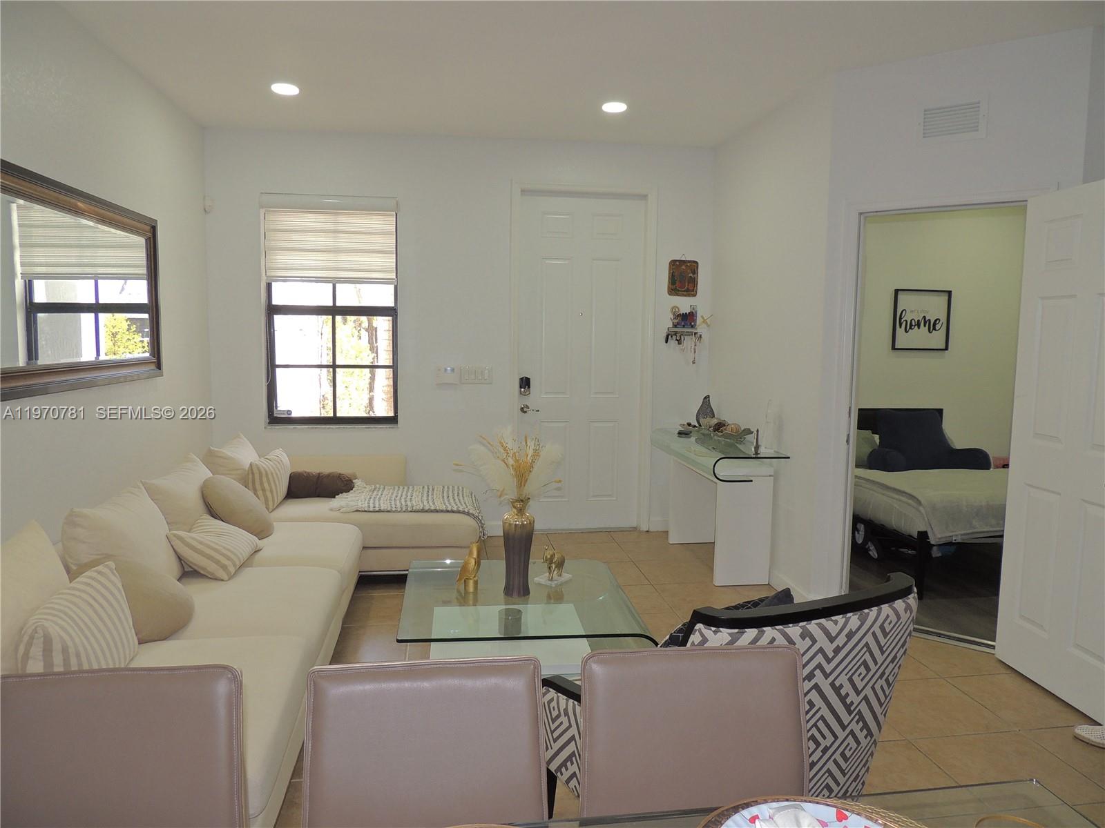 A living room features a white sectional sofa, glass coffee table, and an adjacent bedroom — 11301 NW 88th Ter, Doral FL 33178, DORAL, FL