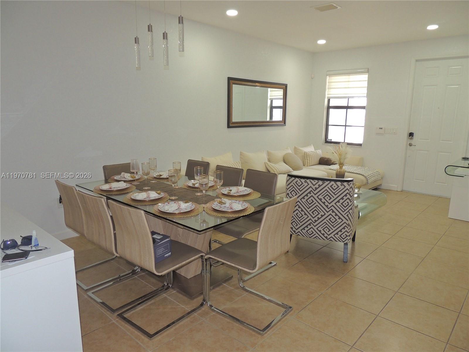 A dining area with a glass-topped table and chairs sits adjacent to a living room — 11301 NW 88th Ter, Doral FL 33178, DORAL, FL