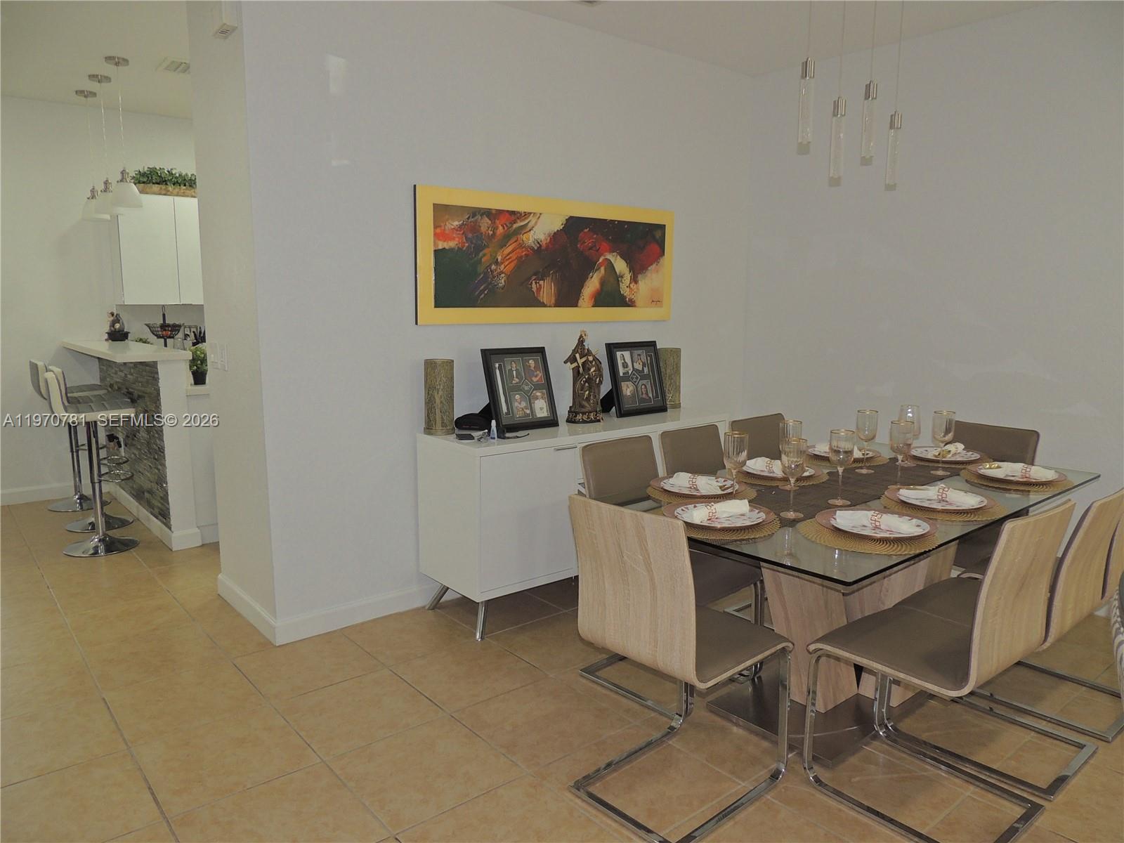 A dining room features a glass-topped table, modern chairs, and a white sideboard — 11301 NW 88th Ter, Doral FL 33178, DORAL, FL