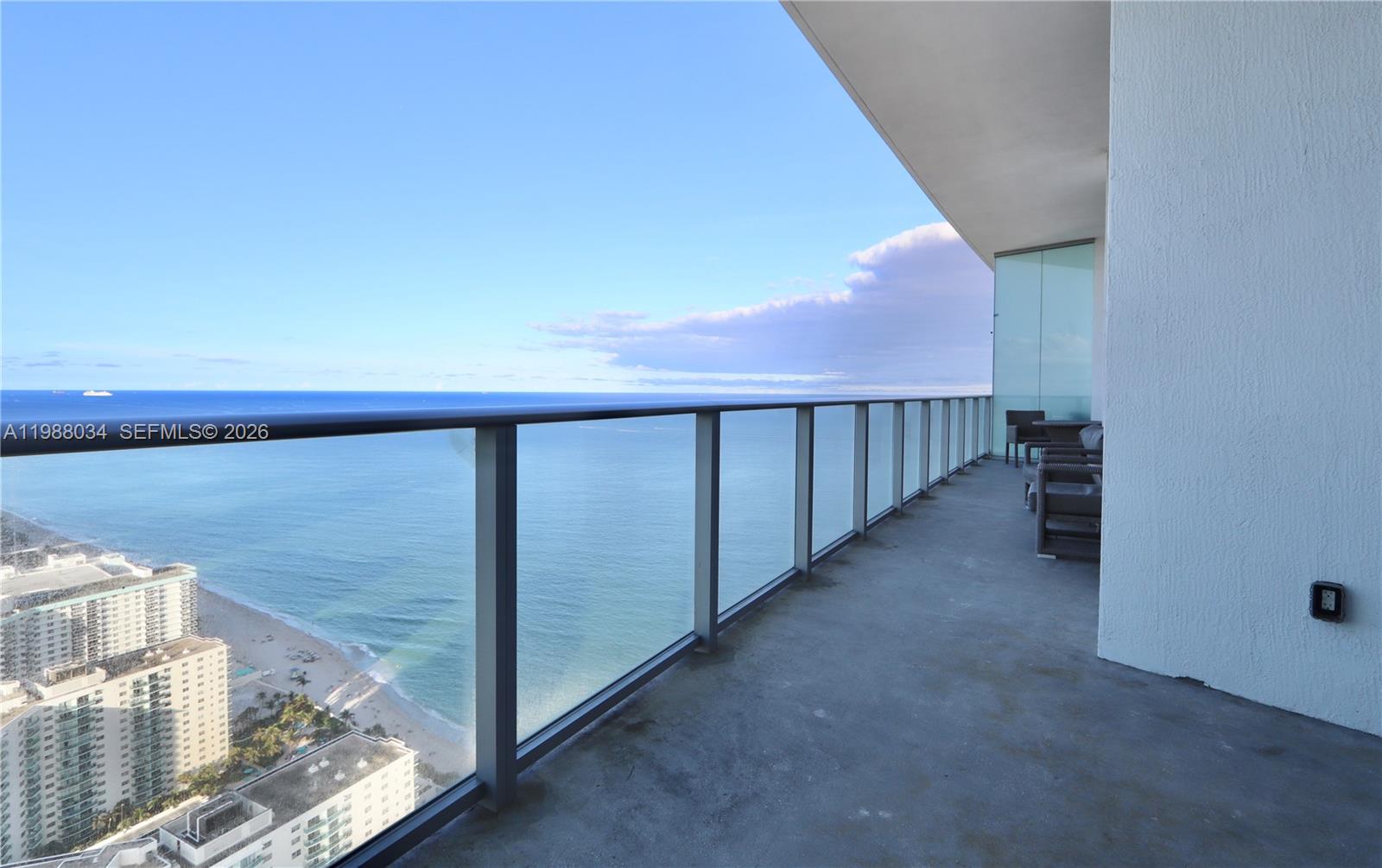 A high-rise balcony features a glass railing overlooking the ocean and a sandy beach — 4111 S Ocean Dr, Hollywood FL 33019, HOLLYWOOD, FL